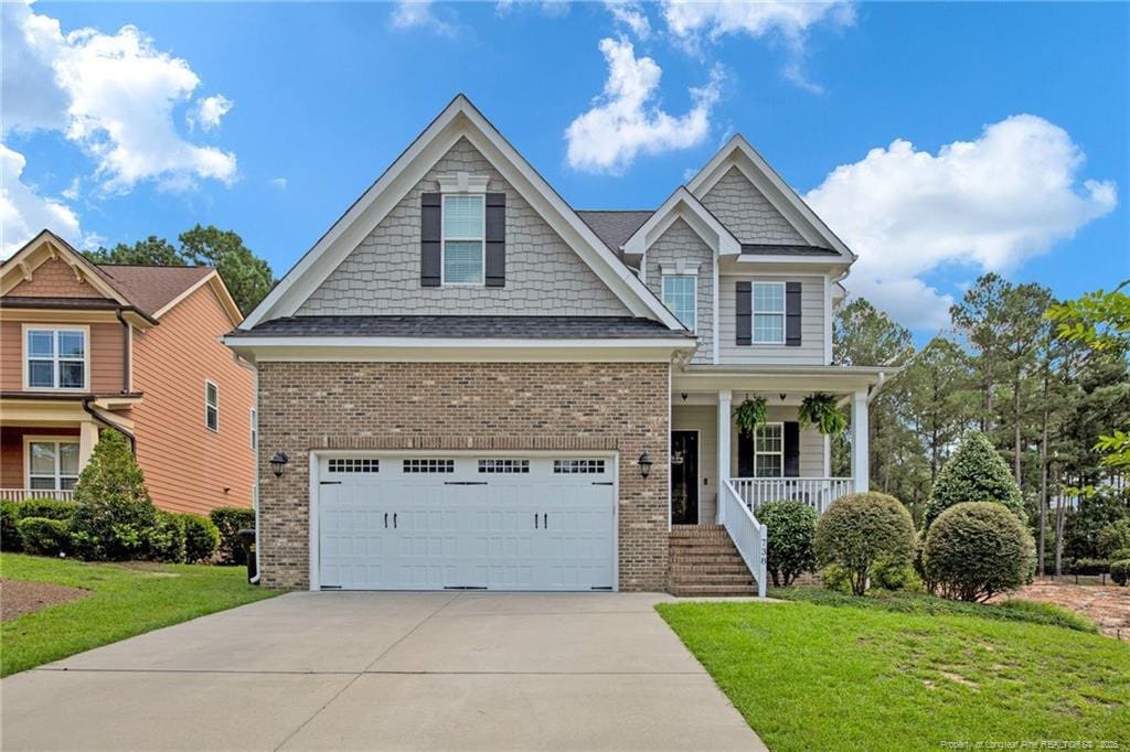 craftsman-style home featuring covered porch, a garage, and a front lawn