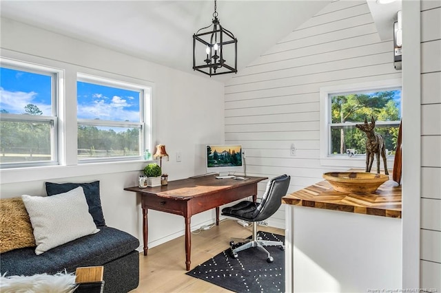 home office with lofted ceiling, an inviting chandelier, and light hardwood / wood-style flooring