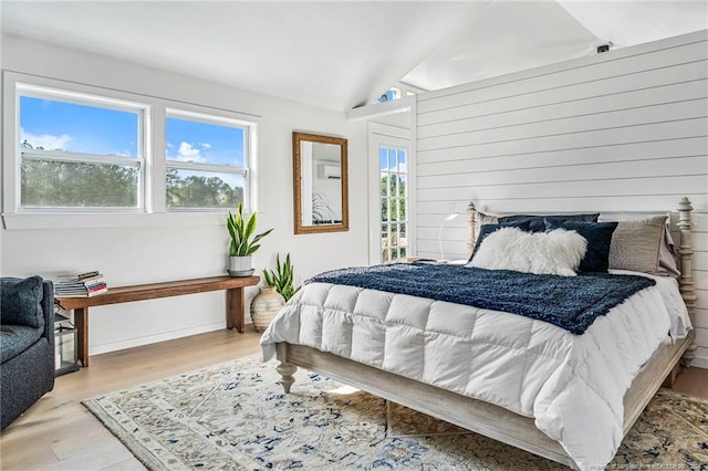 bedroom with lofted ceiling, light hardwood / wood-style flooring, and a wall mounted air conditioner