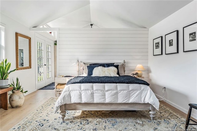 bedroom with vaulted ceiling, french doors, access to exterior, and light hardwood / wood-style floors