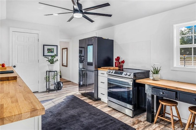 kitchen with stainless steel range with electric stovetop, light hardwood / wood-style flooring, black refrigerator, butcher block counters, and ceiling fan