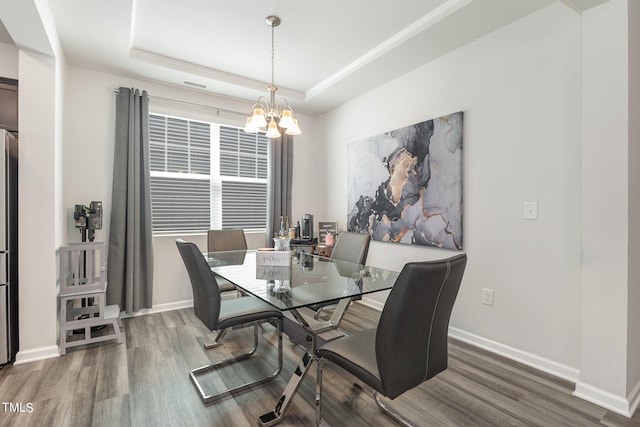 dining space with a notable chandelier, dark hardwood / wood-style floors, and a tray ceiling