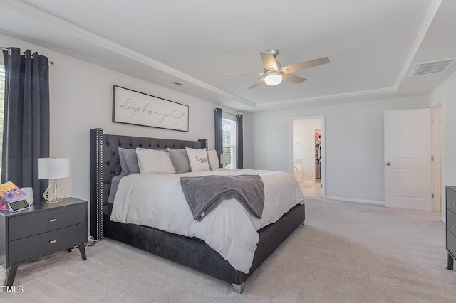 bedroom featuring ensuite bath, a raised ceiling, light carpet, and ceiling fan