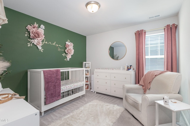 bedroom with light carpet and a nursery area