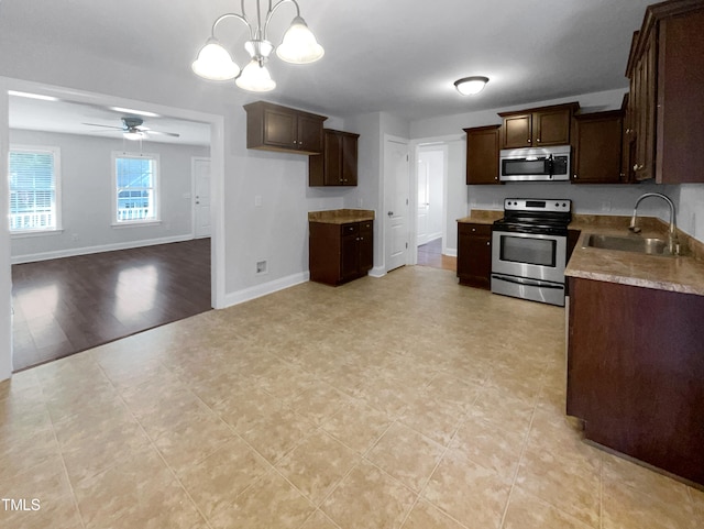 kitchen with light hardwood / wood-style flooring, ceiling fan with notable chandelier, stainless steel appliances, sink, and pendant lighting