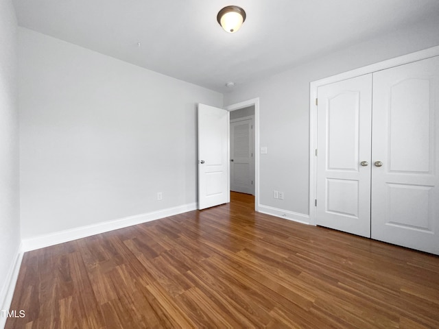 unfurnished bedroom with a closet and dark hardwood / wood-style floors