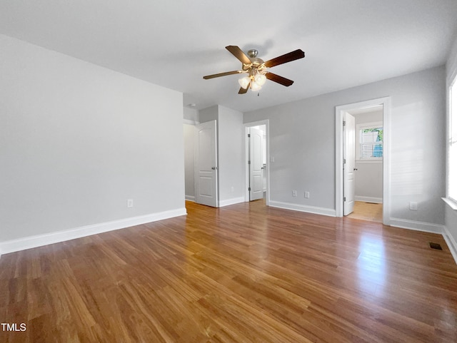 unfurnished bedroom featuring hardwood / wood-style flooring, ensuite bathroom, and ceiling fan