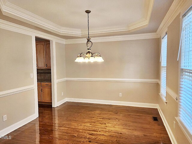 interior space featuring ornamental molding, a raised ceiling, a chandelier, and dark hardwood / wood-style floors