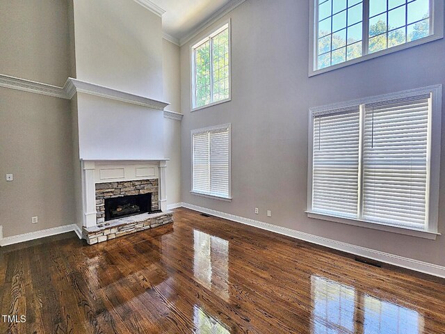 unfurnished living room featuring a towering ceiling, wood-type flooring, and a fireplace