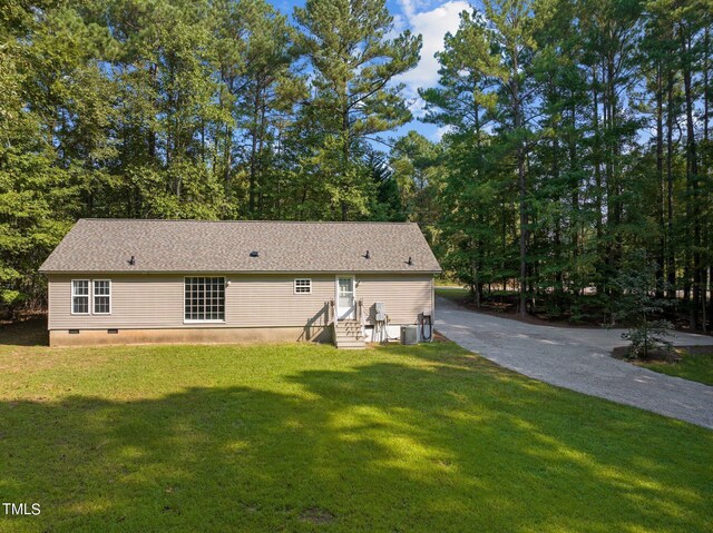 rear view of house featuring cooling unit and a yard