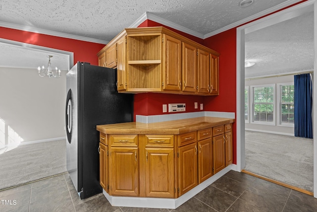 kitchen featuring ornamental molding, a textured ceiling, dark carpet, and stainless steel refrigerator