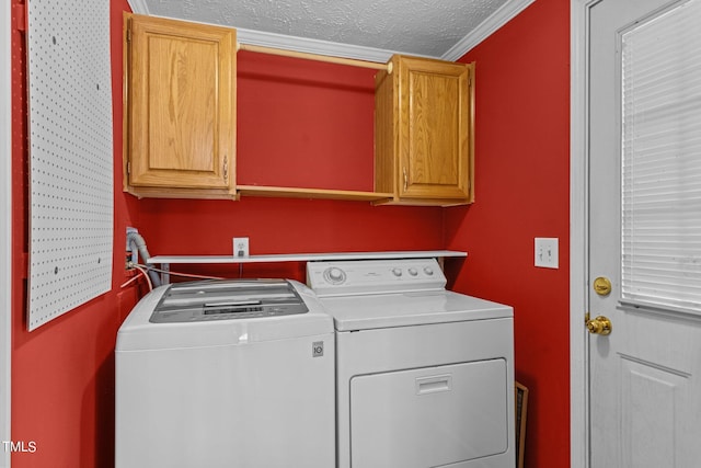 clothes washing area featuring crown molding, a textured ceiling, independent washer and dryer, and cabinets