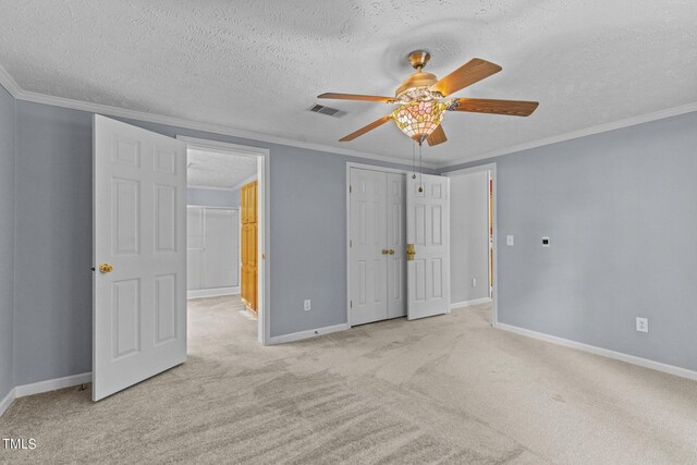 unfurnished bedroom with ceiling fan, light colored carpet, ornamental molding, and a textured ceiling