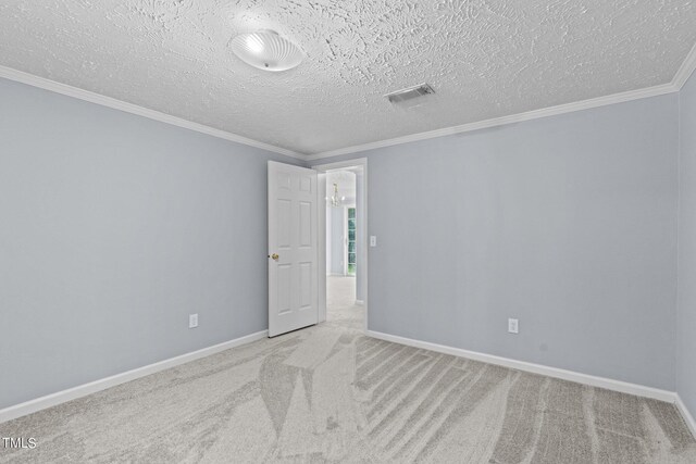 spare room featuring a textured ceiling, crown molding, and light carpet