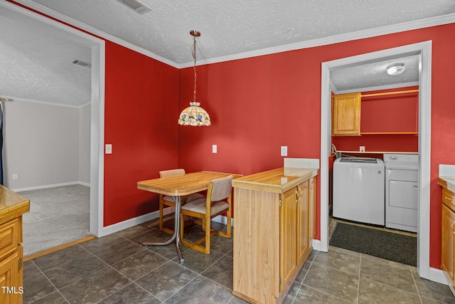 carpeted dining area with crown molding, a textured ceiling, and washer and clothes dryer