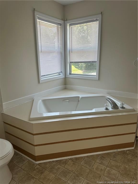 bathroom with a tub, toilet, and tile patterned floors