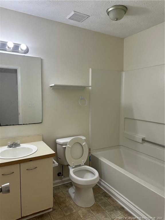 full bathroom featuring tile patterned floors, toilet, tub / shower combination, vanity, and a textured ceiling