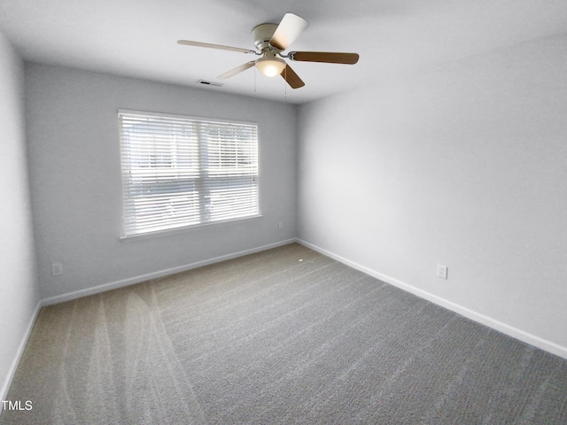 carpeted spare room with baseboards, visible vents, and a ceiling fan