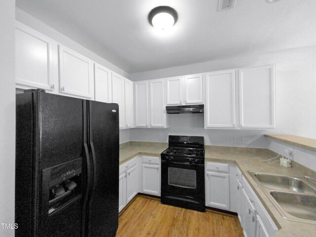 kitchen with light countertops, white cabinetry, a sink, under cabinet range hood, and black appliances