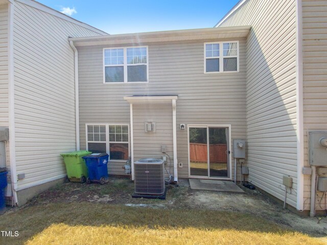 rear view of property featuring a lawn and central AC