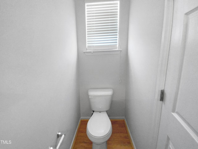 bathroom with toilet, baseboards, and wood finished floors