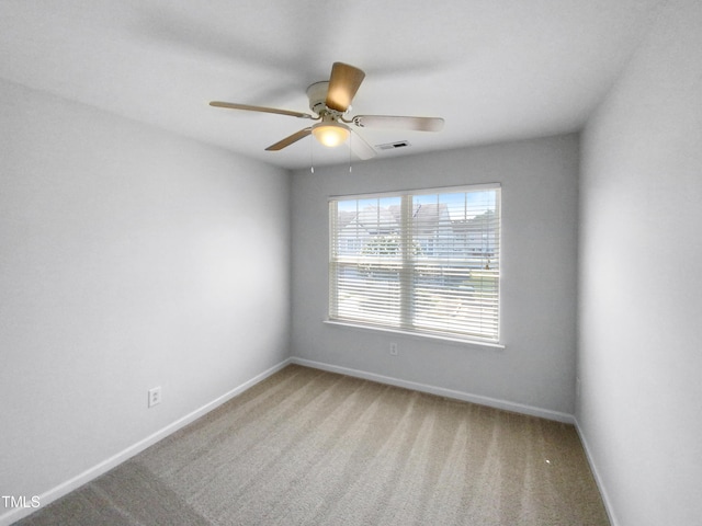 spare room with a ceiling fan, carpet flooring, visible vents, and baseboards