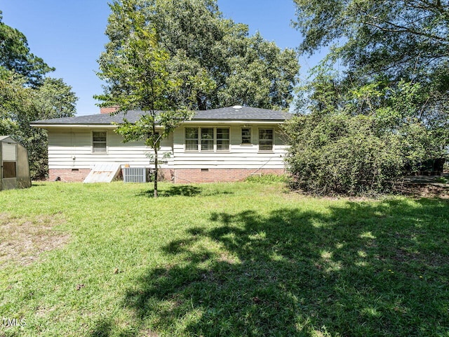 rear view of house with central air condition unit and a yard