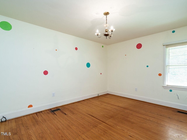 unfurnished room featuring a notable chandelier and hardwood / wood-style floors