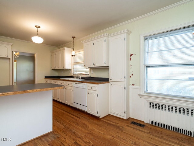 kitchen with a healthy amount of sunlight, white dishwasher, radiator heating unit, white cabinetry, and decorative light fixtures