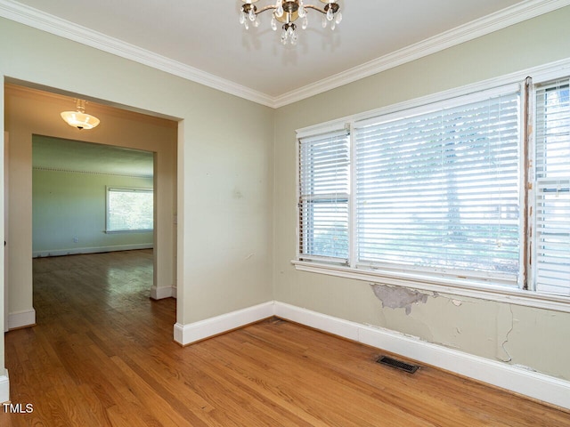 spare room featuring an inviting chandelier, ornamental molding, and wood-type flooring