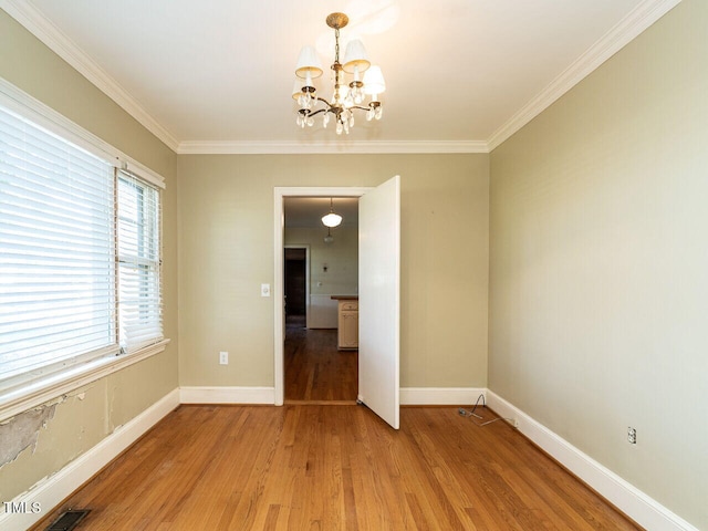 unfurnished room with a notable chandelier, ornamental molding, and hardwood / wood-style flooring