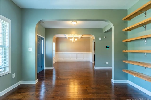 spare room featuring dark hardwood / wood-style floors and a chandelier