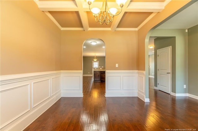 empty room featuring crown molding, dark wood-type flooring, beam ceiling, coffered ceiling, and a notable chandelier