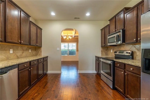 kitchen featuring dark wood-type flooring, appliances with stainless steel finishes, light stone countertops, and tasteful backsplash