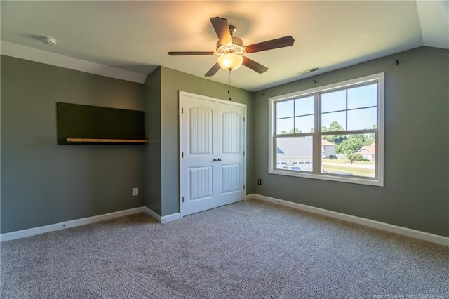 unfurnished bedroom featuring ceiling fan, lofted ceiling, carpet floors, and a closet