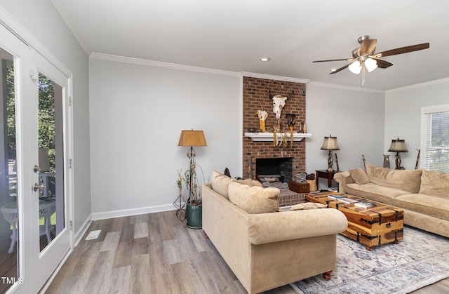 living room featuring light hardwood / wood-style floors, a brick fireplace, plenty of natural light, and crown molding