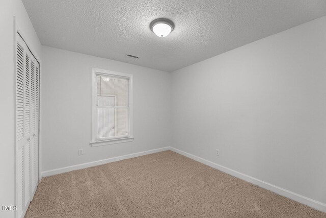 unfurnished bedroom featuring a textured ceiling, carpet floors, and a closet