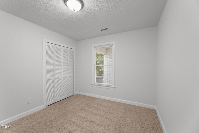 unfurnished bedroom featuring carpet, a textured ceiling, and a closet