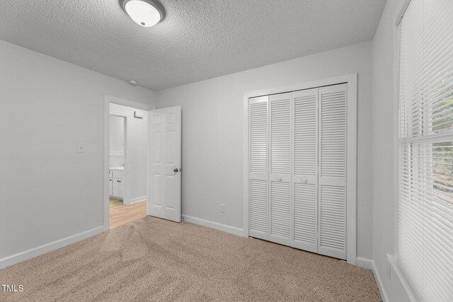 unfurnished bedroom with carpet flooring, a textured ceiling, and a closet