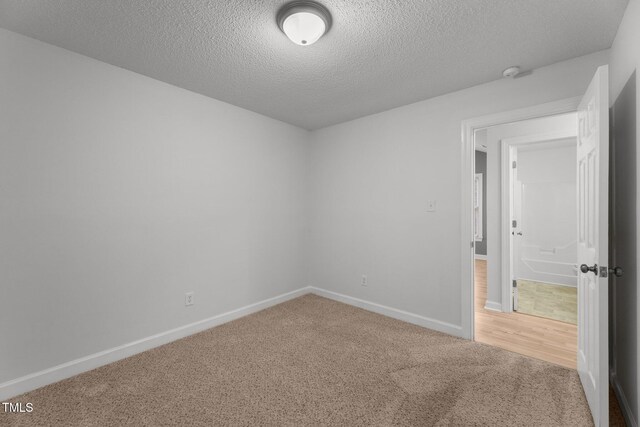 unfurnished room featuring carpet and a textured ceiling