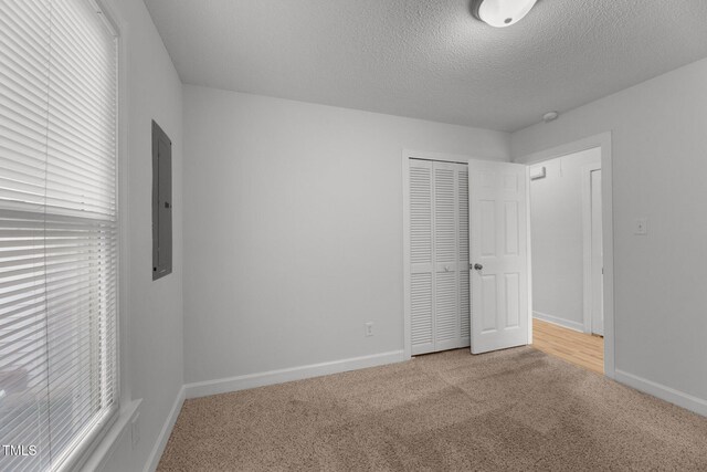 spare room with electric panel, light carpet, and a textured ceiling