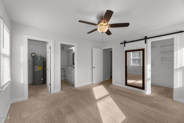 unfurnished bedroom featuring a barn door, electric water heater, ensuite bath, and multiple windows