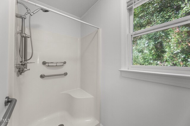 bathroom featuring a shower, a textured ceiling, and ornamental molding