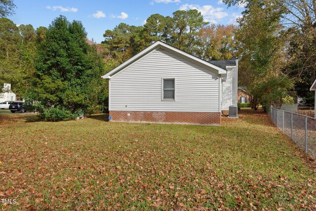 view of side of home featuring a lawn and central AC