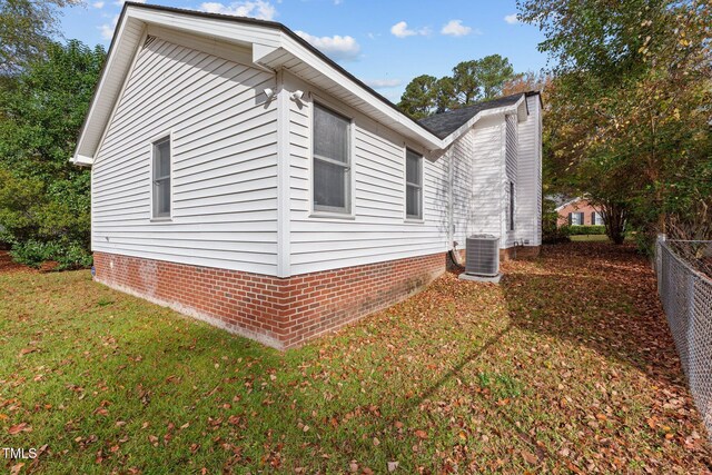 view of side of home featuring a yard and central AC unit