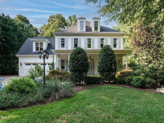 colonial-style house with a garage, a front lawn, and covered porch