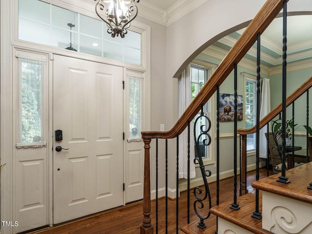 foyer with ornamental molding, a healthy amount of sunlight, a notable chandelier, and hardwood / wood-style flooring