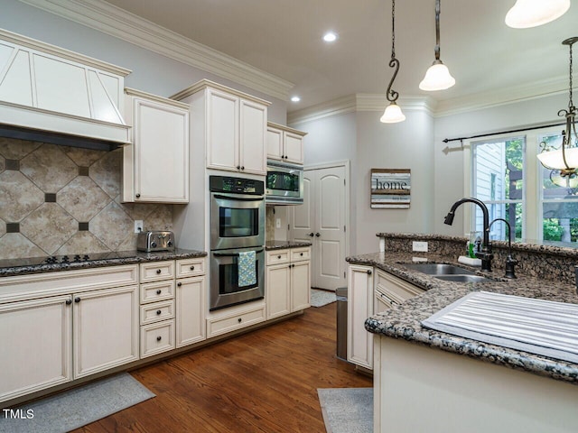 kitchen featuring dark hardwood / wood-style floors, hanging light fixtures, stainless steel appliances, sink, and dark stone counters