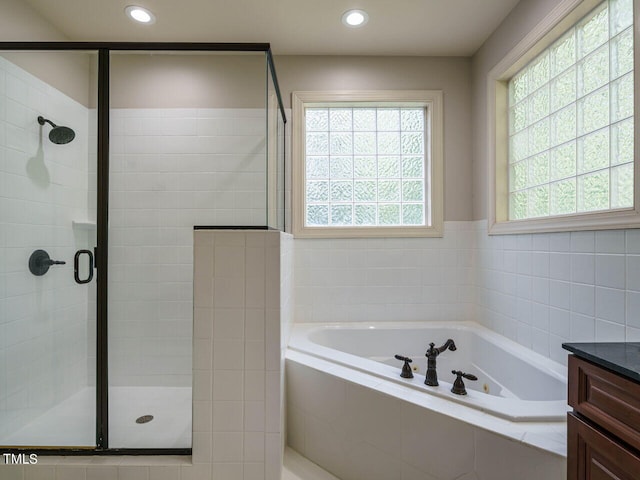 bathroom featuring vanity, a wealth of natural light, and plus walk in shower