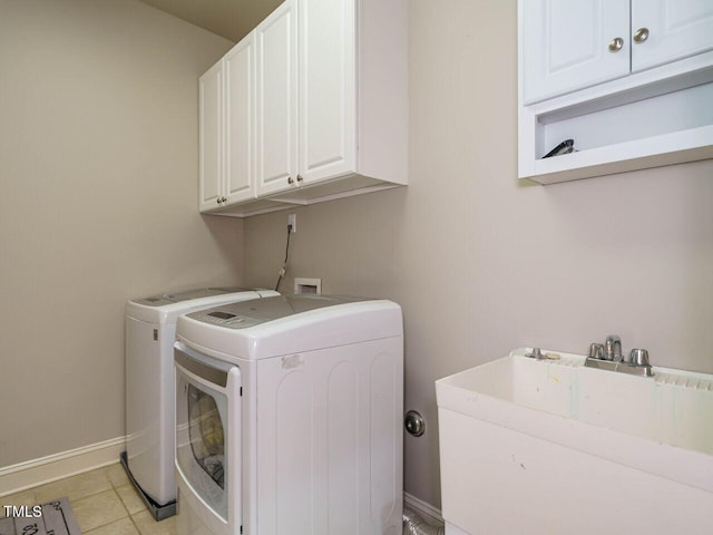 laundry area with light tile patterned floors, independent washer and dryer, cabinets, and sink